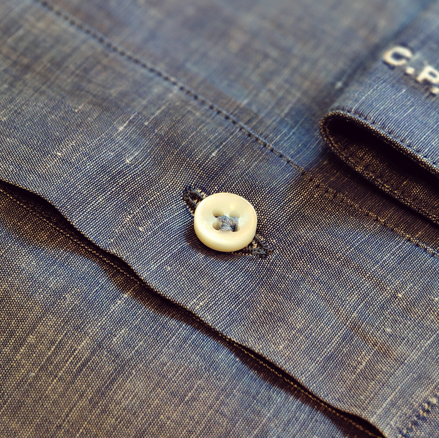 Dettaglio di un bottone acucito a fiore di una camicia uomo su misura presso l'Atelier ICONAZERO a Milano